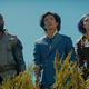 Mustafa Shakir's Jet Black, John Cho's Spike Spiegel, and Daniella Pineda's Faye Valentine stand in a row amidst bushes staring at something unseen.